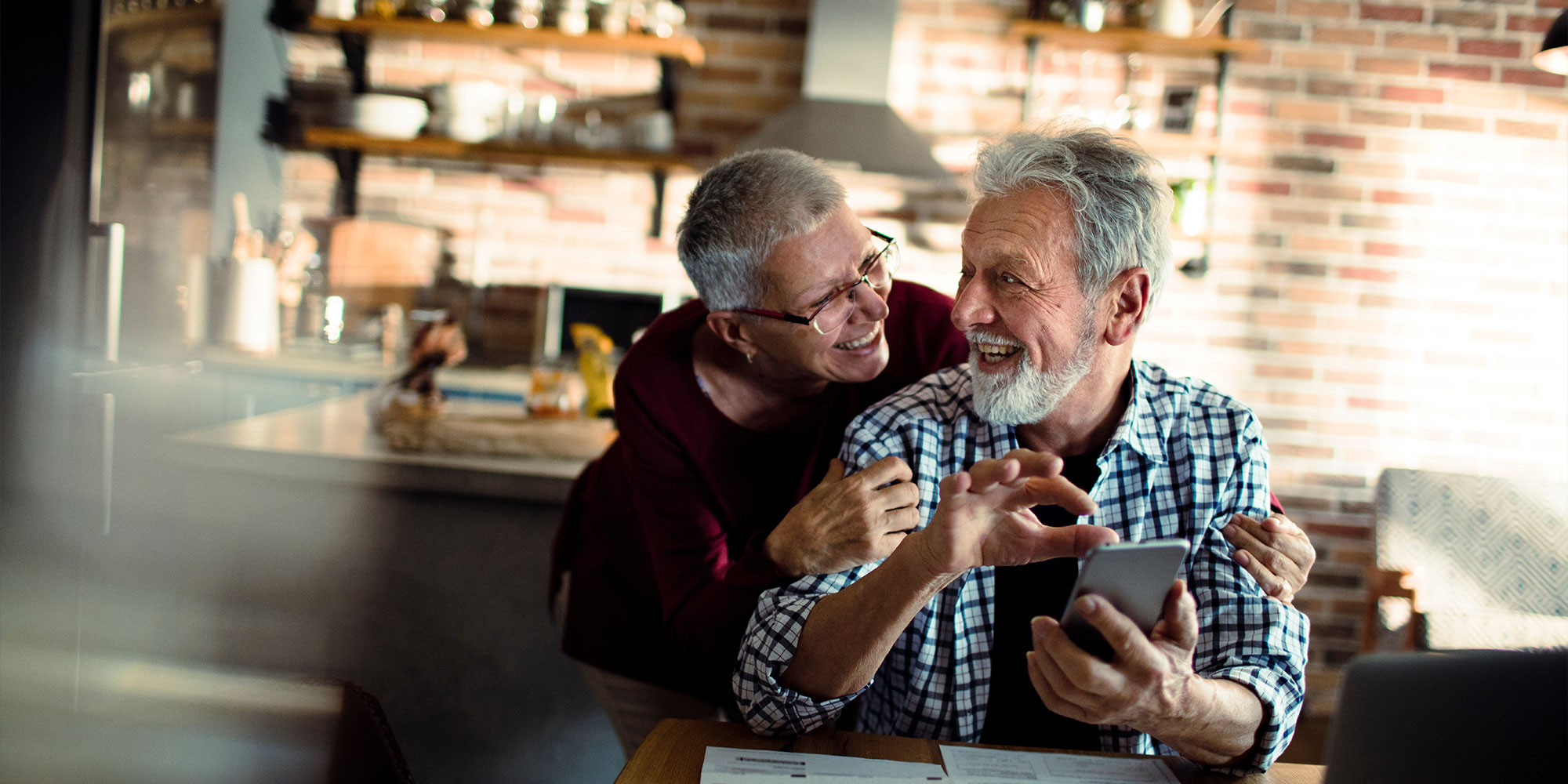 Couple smiling while going over dental finances within their home
